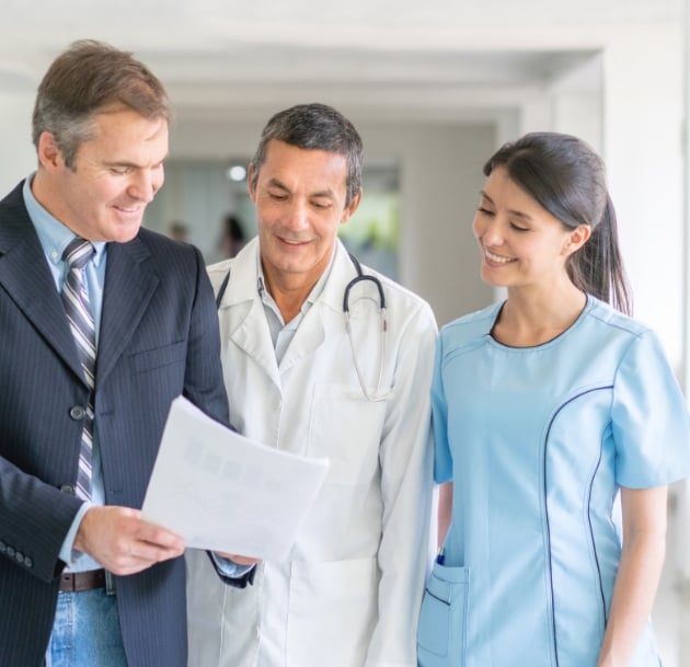 doctors and businessperson talking over a packet of paper